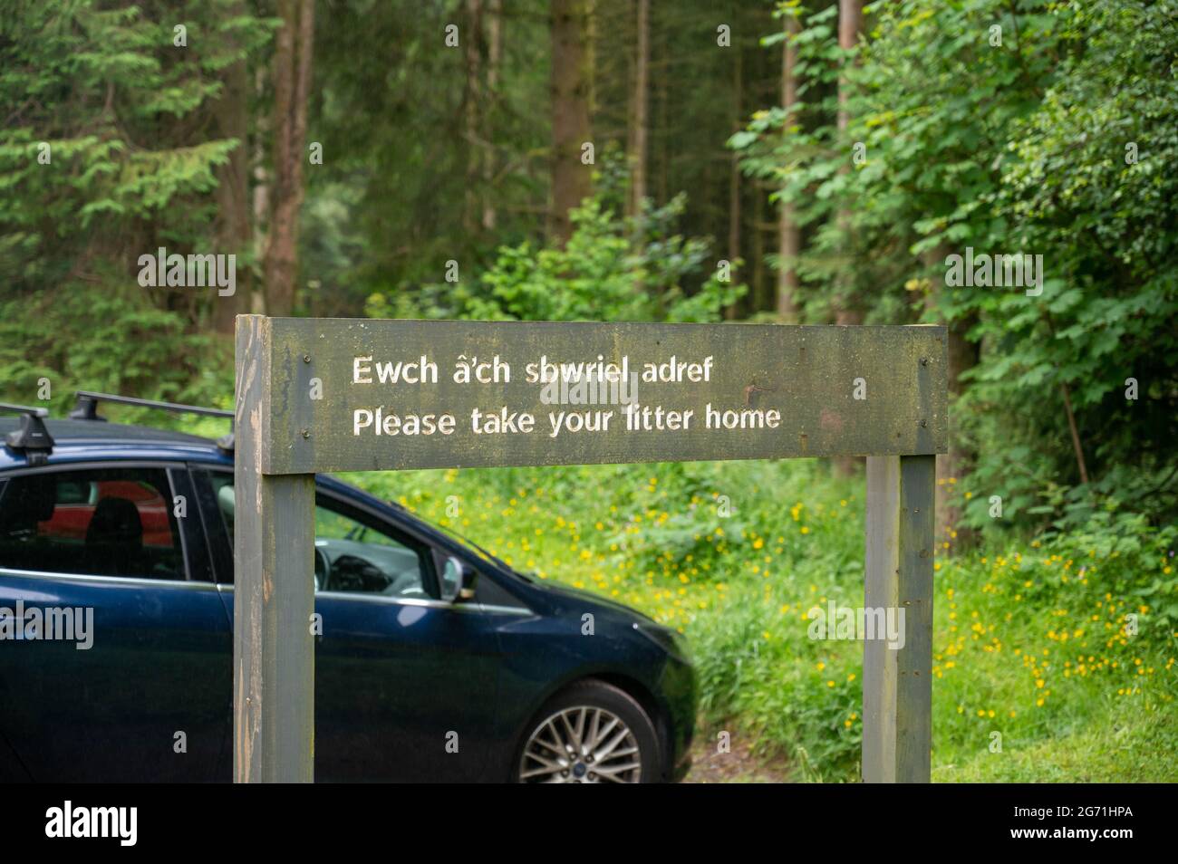 A wooden sign in Welsh and English saying “Please take your litter home” Stock Photo