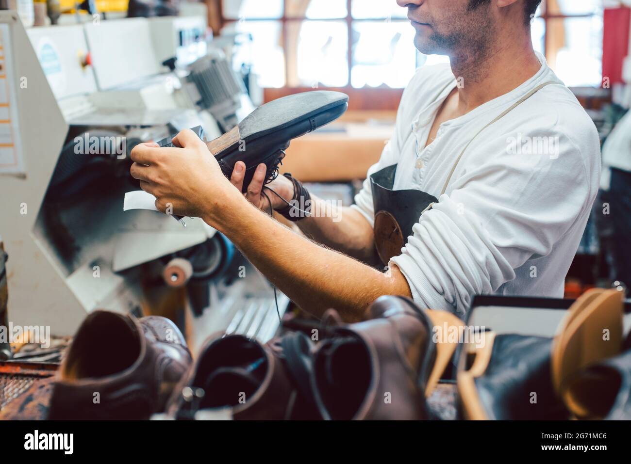 Shoemaker roughing the sole of a leather shoe at the machine Stock Photo