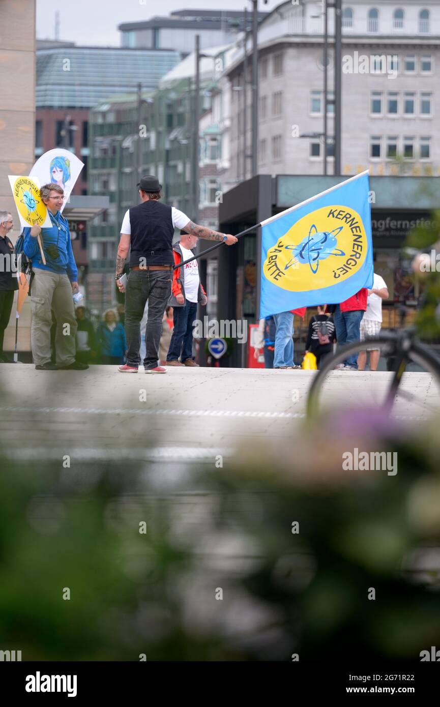 Hamburg, Germany. 10th July, 2021. Demonstrators hold flags and signs reading 'Nuclear energy yes please'. Supporters of the association 'Nuklearia' have gathered at the Jungfernstieg in Hamburg to demonstrate for the preservation of nuclear energy. The aim, they say, is to draw attention to what they see as the harmful consequences for the climate of shutting down nuclear power plants. Credit: Jonas Walzberg/dpa/Alamy Live News Stock Photo