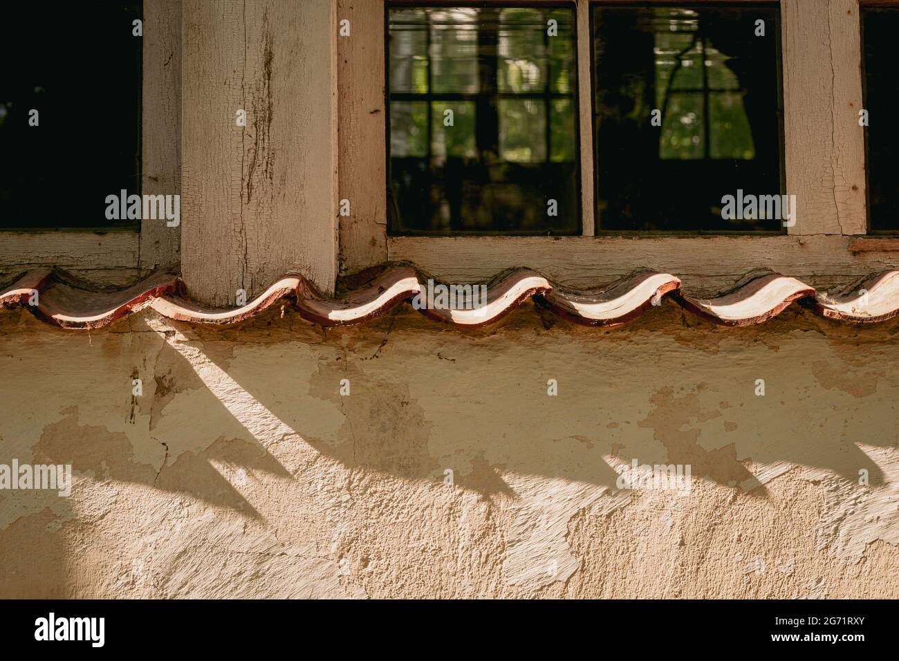 An old window in an old building of the last century. shadows from windowsill on wall. orange yellow painted wall Stock Photo