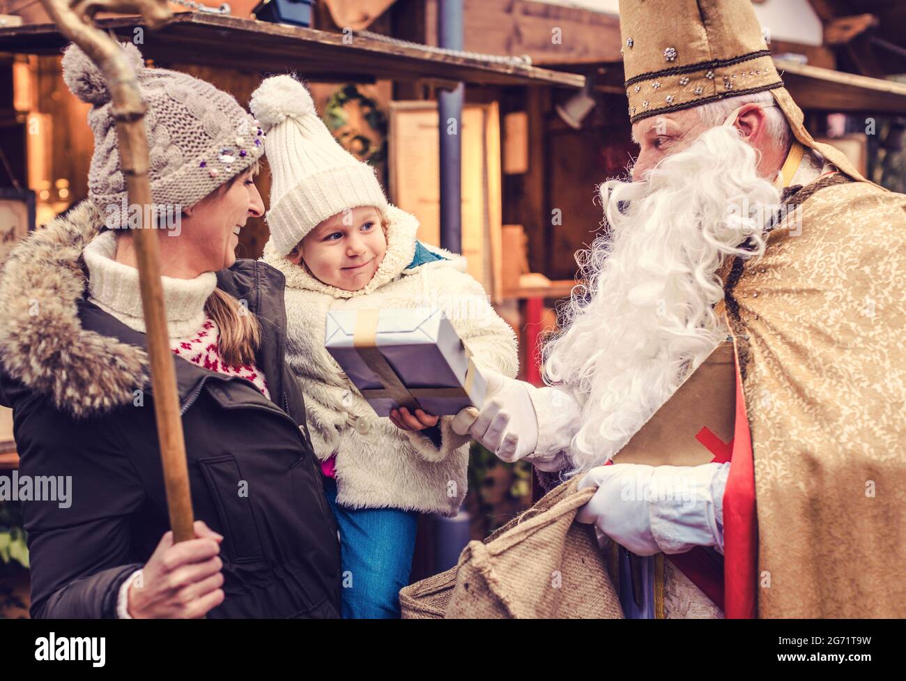 St Nicholas with his staff and presents meeting a family on the Christmas market Stock Photo