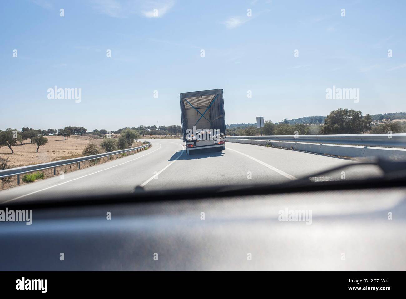 Driving behind building materials truck loaded with steel framework bars. Oversize load length restrictions concept Stock Photo