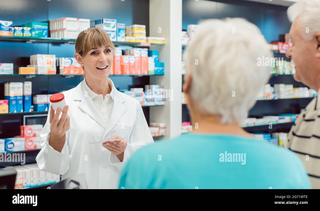 Chemist advising senior couple on a prescription drug in her pharmacy Stock Photo
