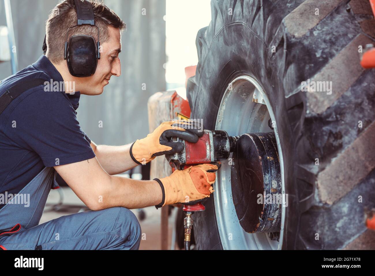 Farm machine mechanic working on wheel with power tool Stock Photo Alamy