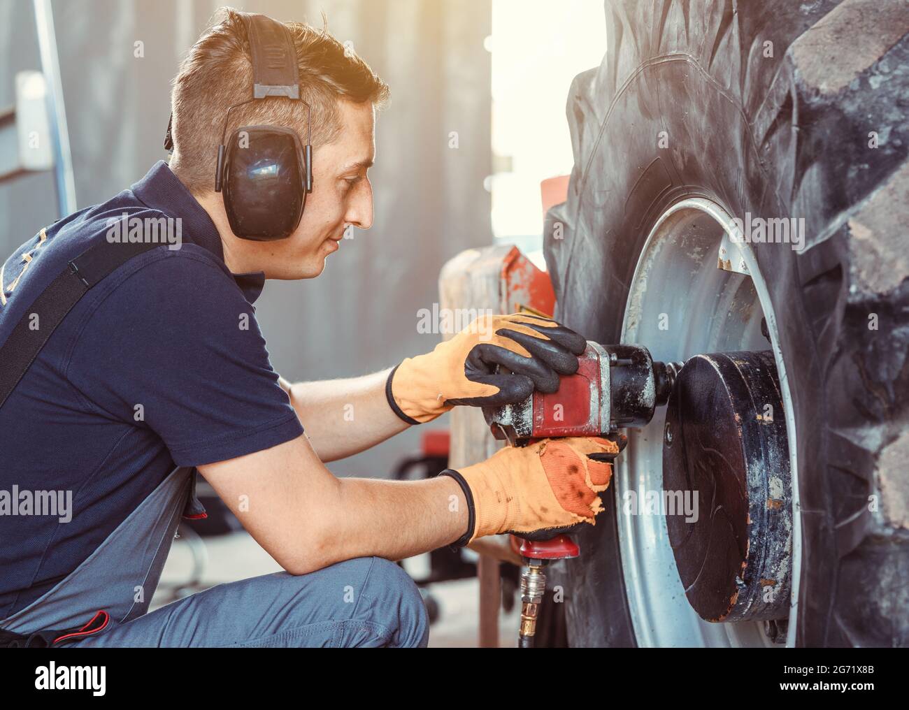 farm machine mechanic working on wheel with power tool Stock Photo Alamy