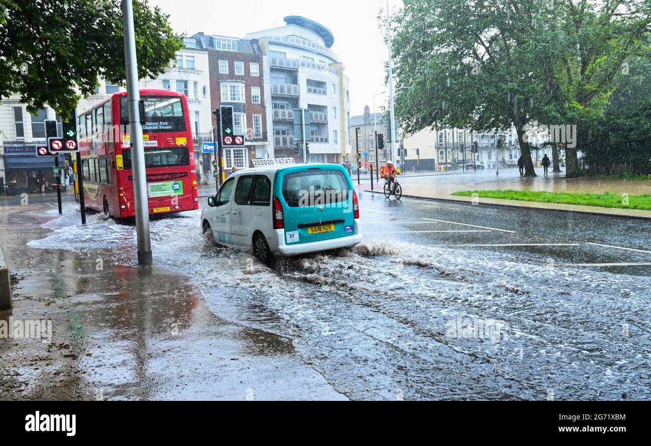 Brighton, UK. 10th July 2021. - Traffic and cyclists negotiate flash flooding in Brighton city centre as heavy rain sweeps across the South East today : Credit Simon Dack / Alamy Live News Stock Photo