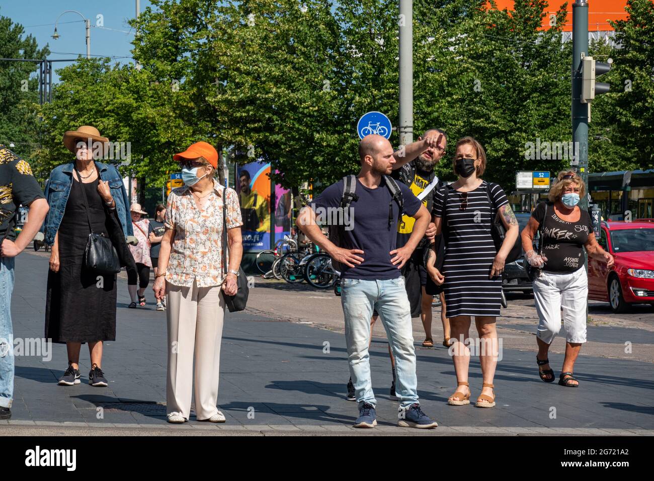 Incidental people standing at traffic light, some wearing facemasks, in Helsinki, Finland Stock Photo