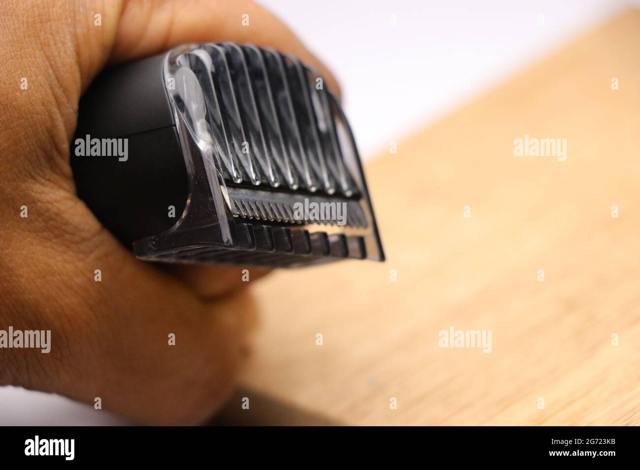 cordless beard trimmer held in hand with closeup of trimmer blades and