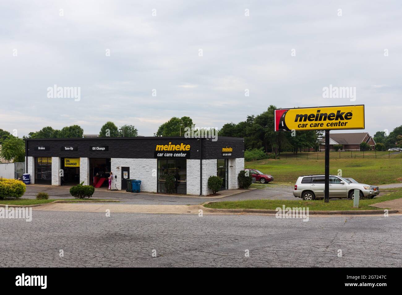 HICKORY, NC, USA-7 JULY 2021:  A Meineke Car Care Center, a car repair chain with more than 900 locations.  Buidiing, signs, parking lot.  One person. Stock Photo