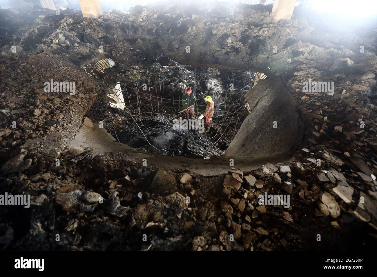 July 10, 2021.Dhaka,Bangladesh: Bangladeshi firefighters remove fire in burnt rubble and searching missing bodies after in a fire at the factory of Ha Stock Photo