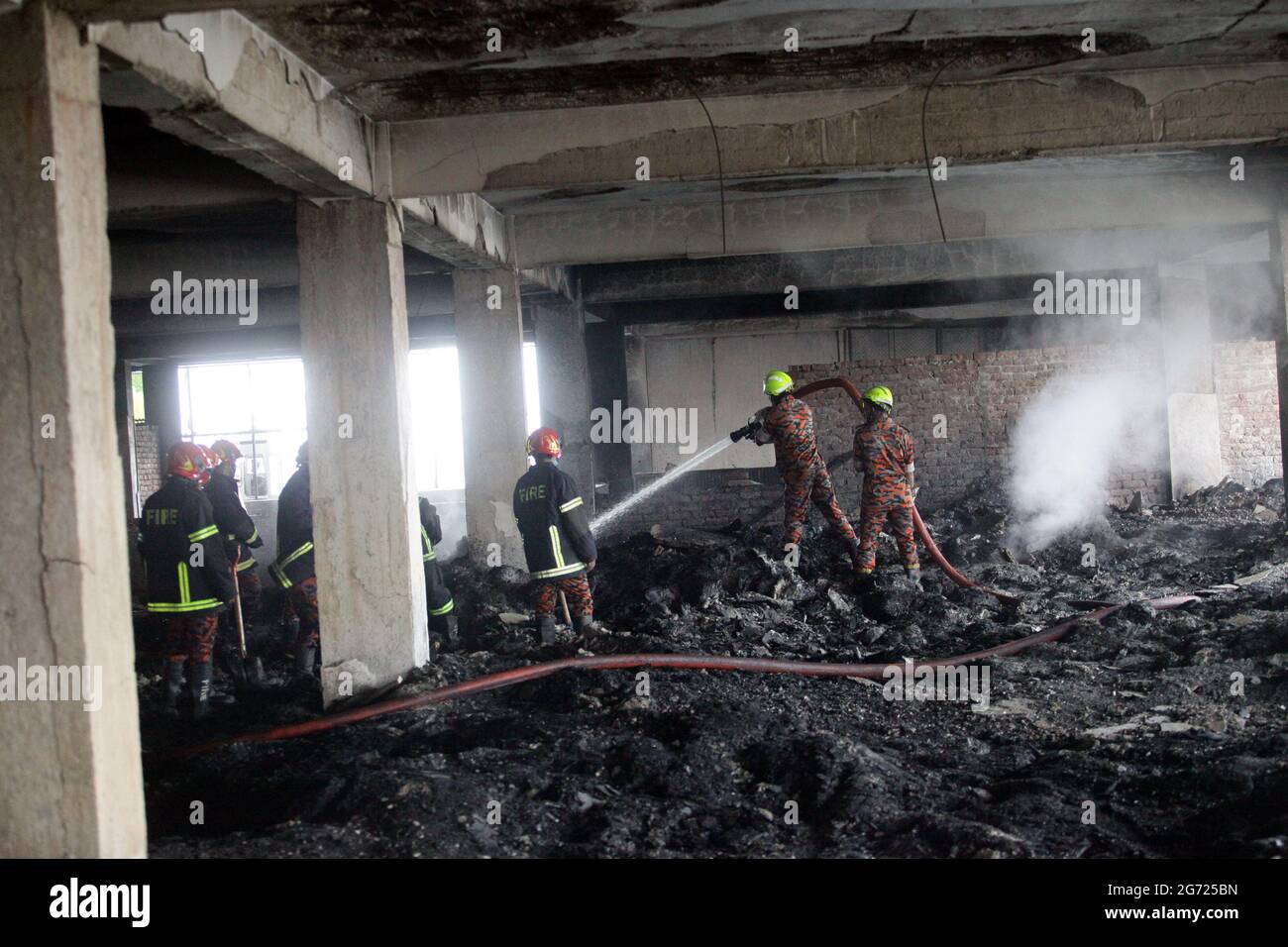 July 10, 2021.Dhaka,Bangladesh: Bangladeshi firefighters remove fire in burnt rubble and searching missing bodies after in a fire at the factory of Ha Stock Photo