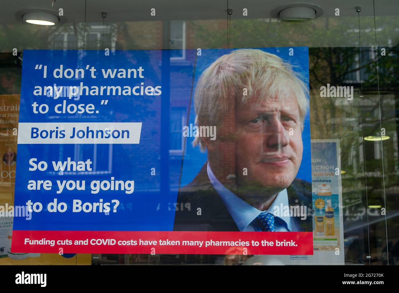 Uxbridge, London Borough of Hillingdon, 9th July, 2021. A message to Boris Johnson in a pharmacy window in Uxbridge about funding cuts and Covid-19 costs taking pharmacies to the brink. Credit: Maureen McLean/Alamy Stock Photo