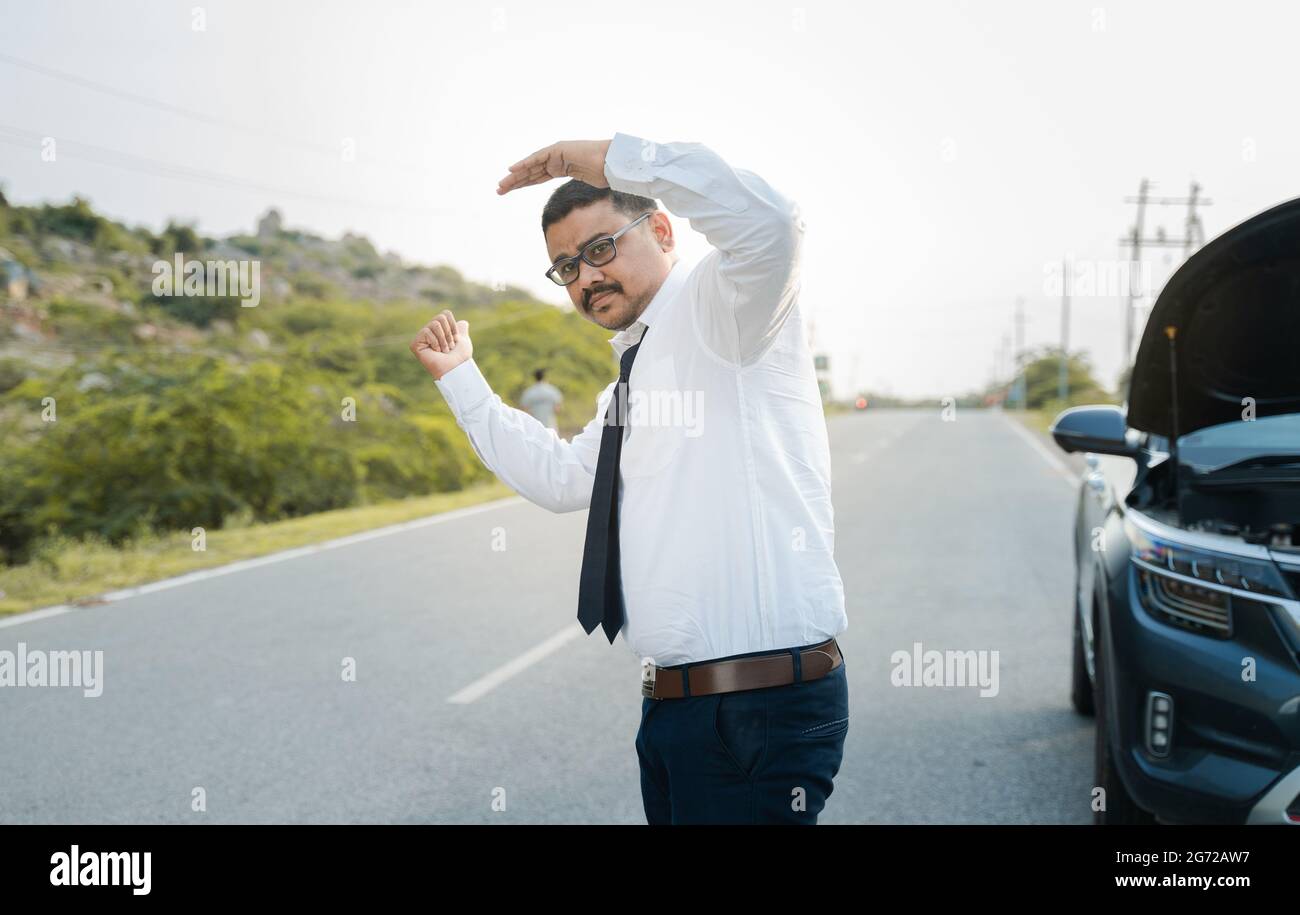 Businessman asking for lift or hitchhiking due to car breakdown while traveling - concept of asking help while commuting Stock Photo