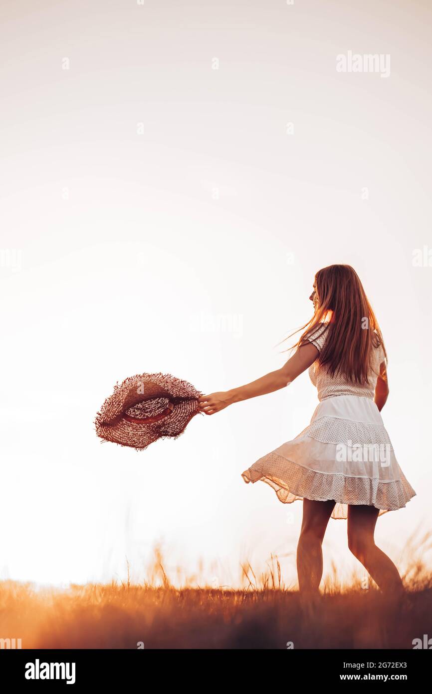 Outdoors photo of young, teen, ginger girl running through the field, holding a summer hat. Copy space Stock Photo