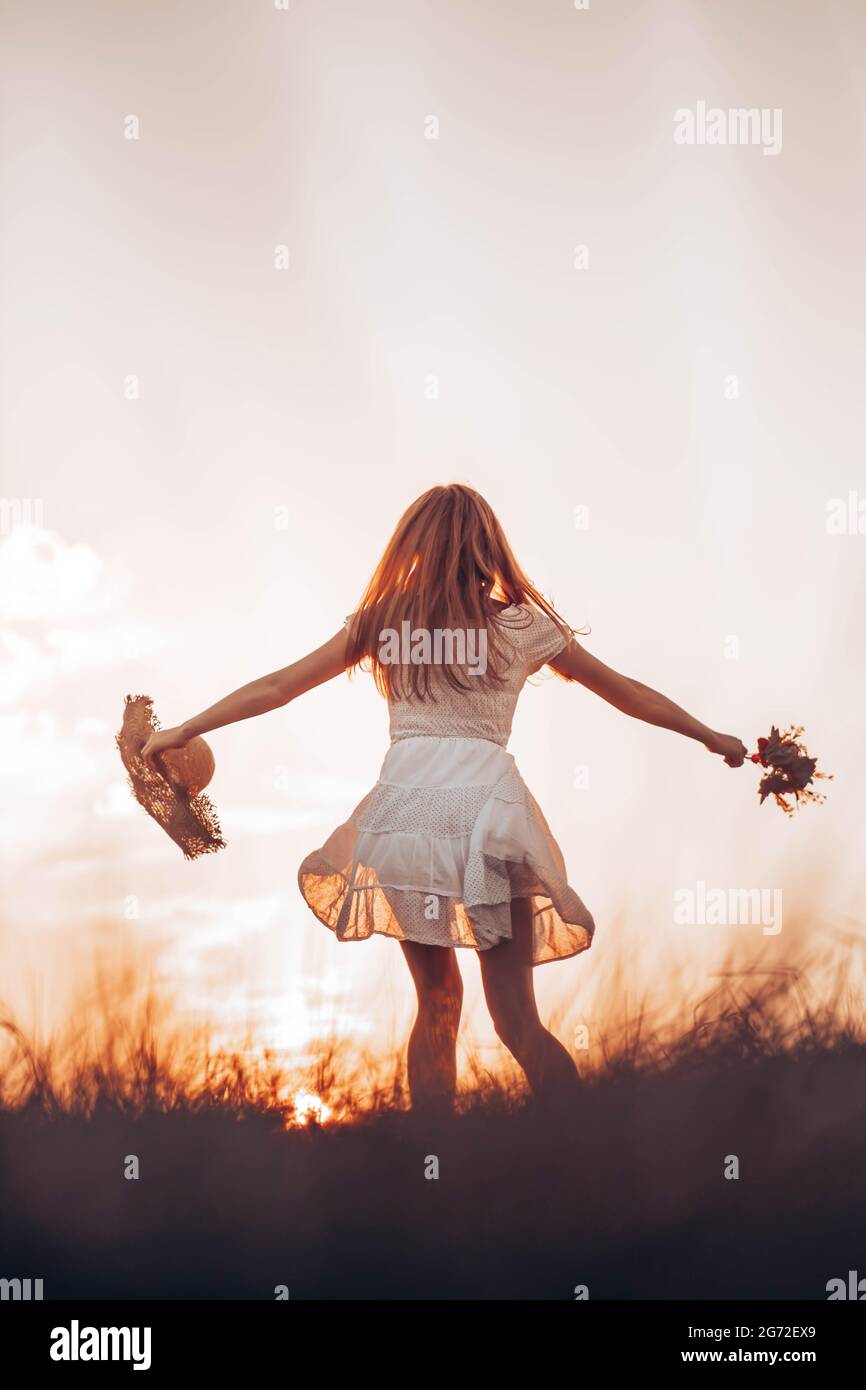 Outdoors photo of young, teen, ginger girl running through the field, holding a summer hat. Copy space Stock Photo