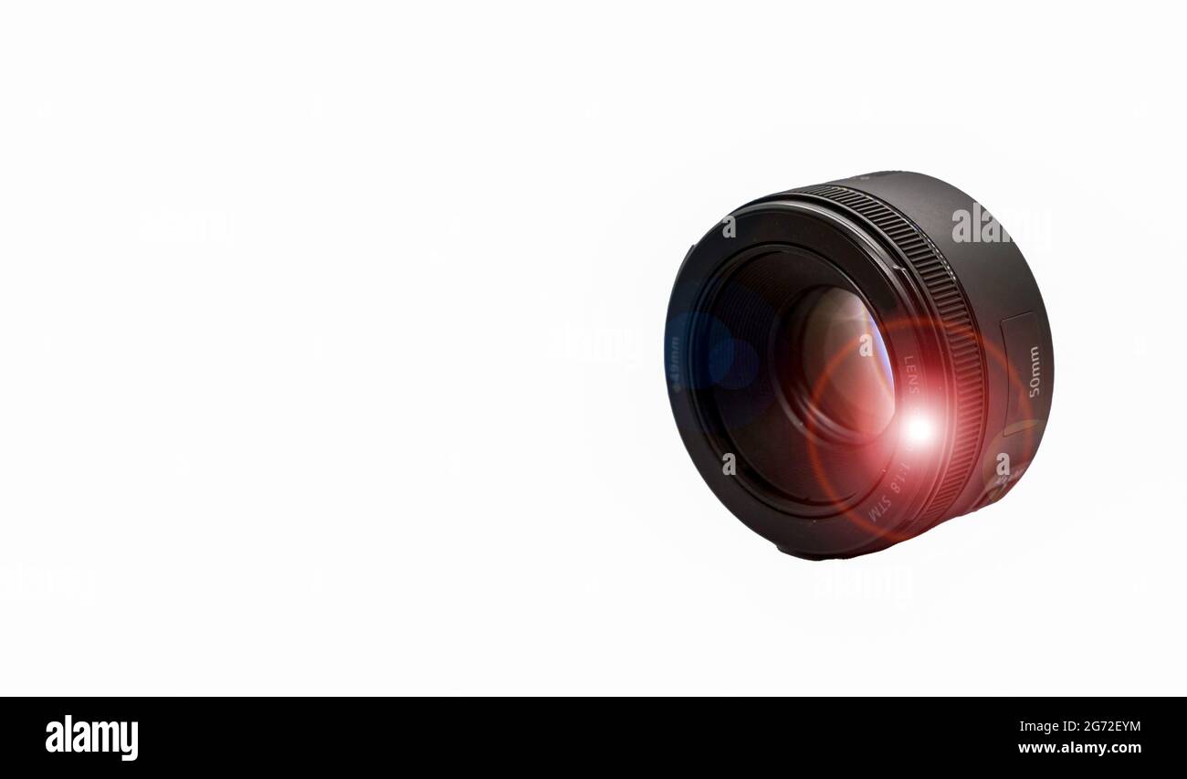 A small round DSLR camera lens with lens flare isolated on a white