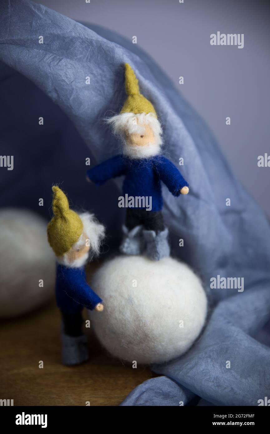 Two knitted fictional characters - dwarves dressed in blue on a fluffy white ball Stock Photo