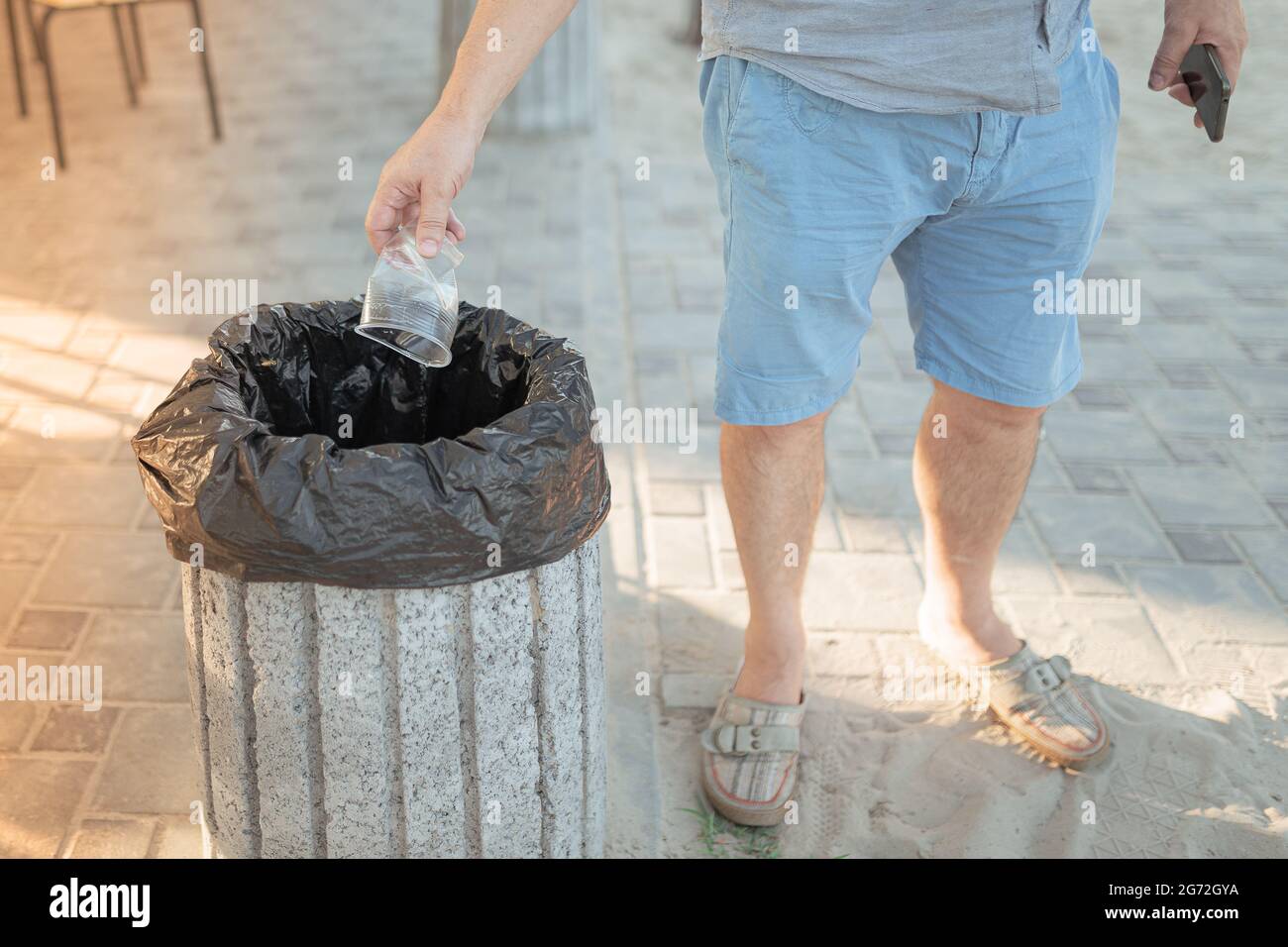 A man throws an empty plastic cup into a trash can Stock Photo