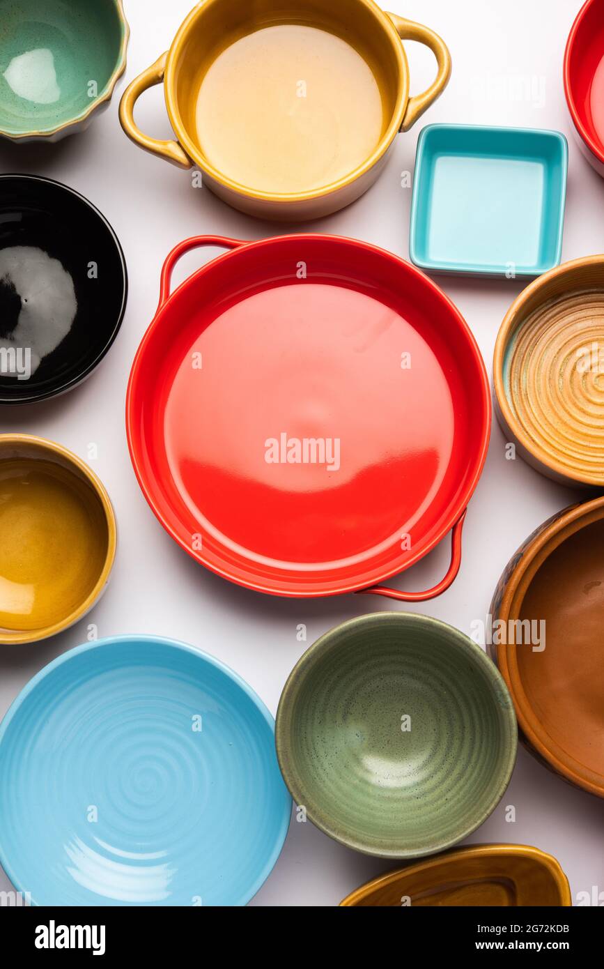 Collection of empty colorful ceramic bowls. Group of utensils captured from above, top view, flat lay against white background Stock Photo