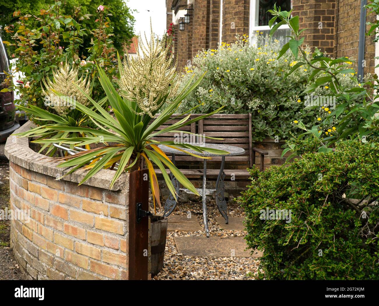 Small table and chair in a compact garden Stock Photo - Alamy