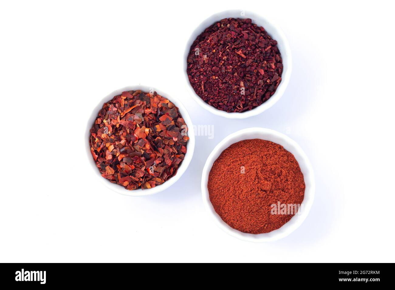 Set of three bowls with red spices isolated on white background. Chilli, pepper powder, dried tomatoes top view Stock Photo