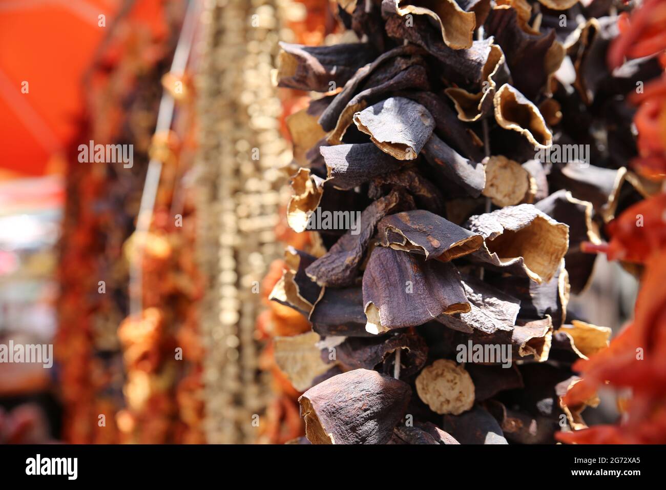 Close up of dried eggplants hanging on a string for sale outdoors, under sunlight. Stock Photo