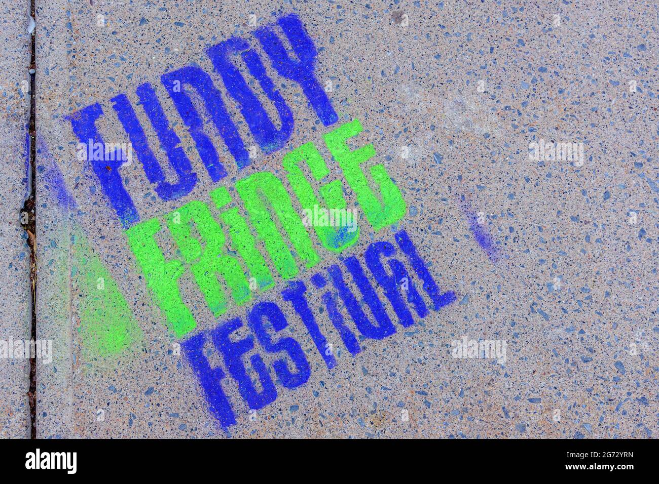 Saint John, NB, Canada - August 14, 2017: A Fundy Fringe Festival logo painted in blue and green on a concrete sidewalk. Stock Photo