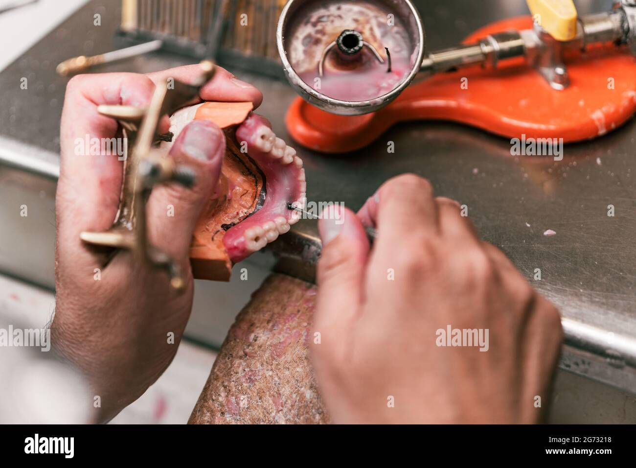 Hands of a dental technician fixing the paste on a dental prosthesis Stock Photo