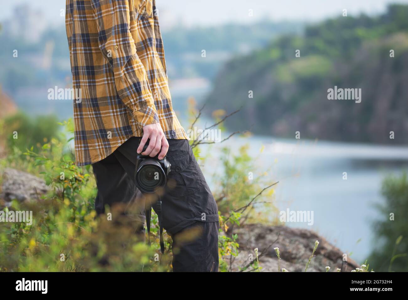 Young adult in shirt holding a camera for landscape photography. Travel concept Stock Photo