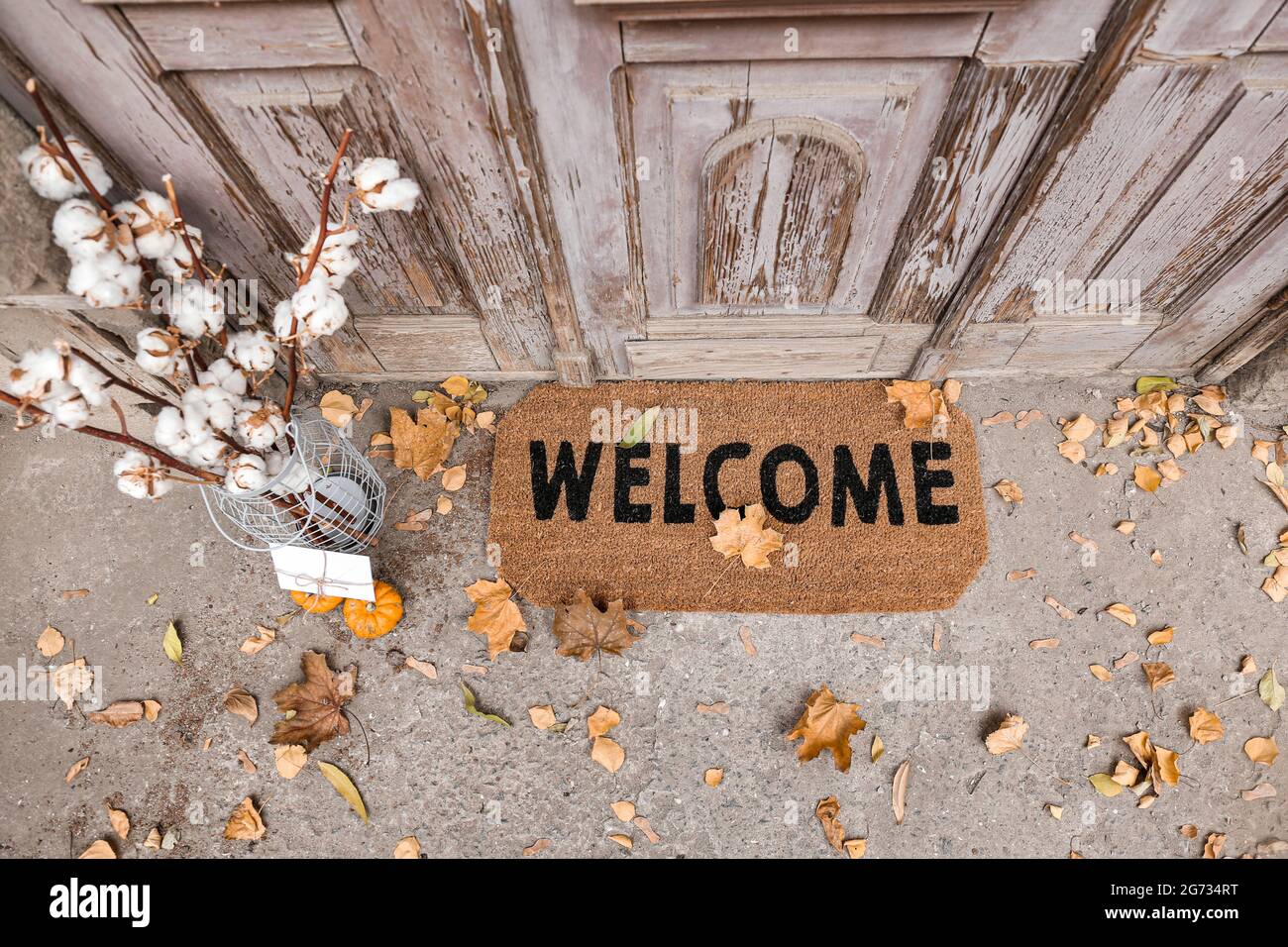 https://c8.alamy.com/comp/2G734RT/doormat-with-cotton-flowers-and-letter-near-entrance-of-house-on-autumn-day-2G734RT.jpg