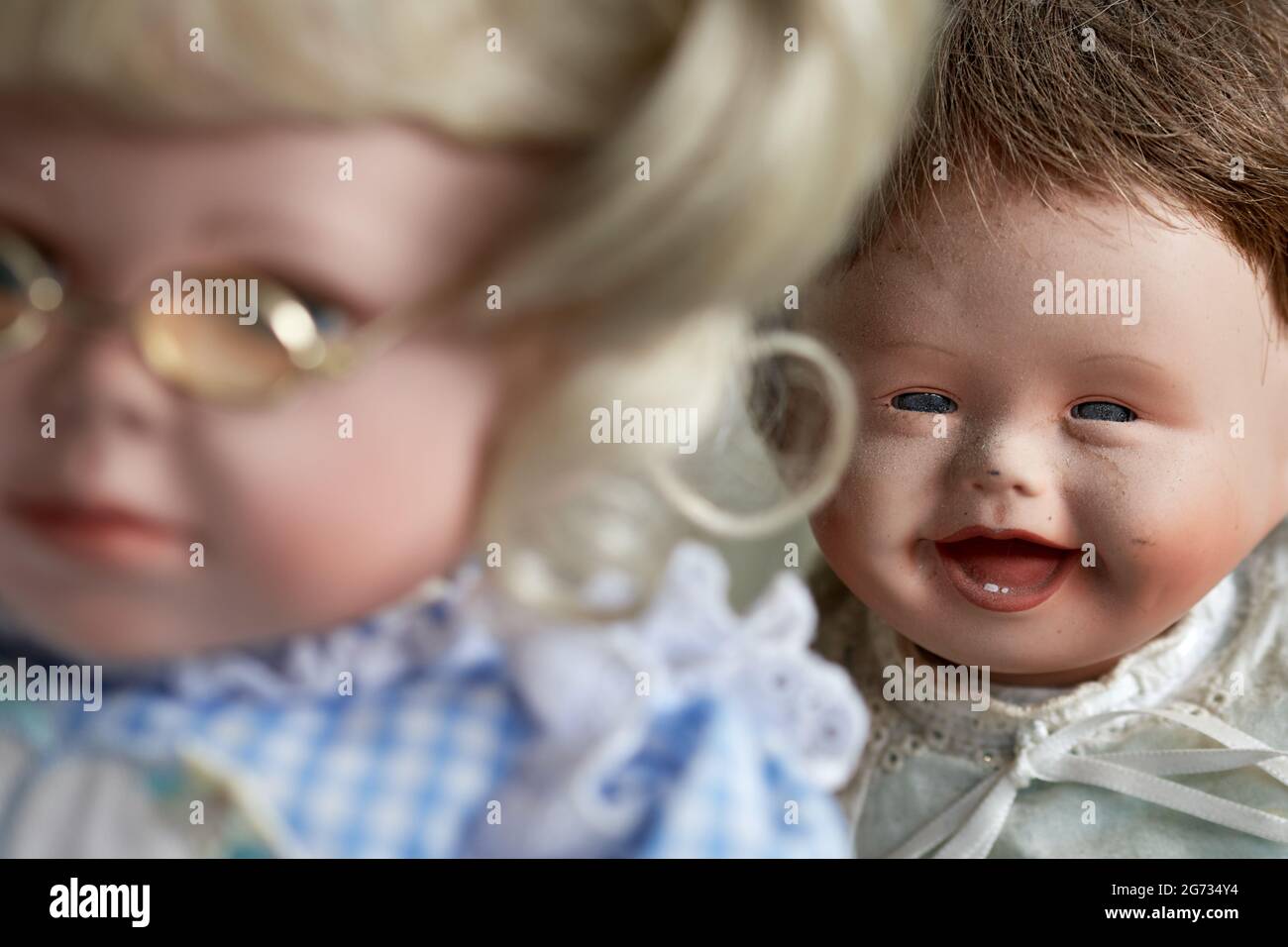 Vintage baby doll laughing at girl doll with glasses Stock Photo