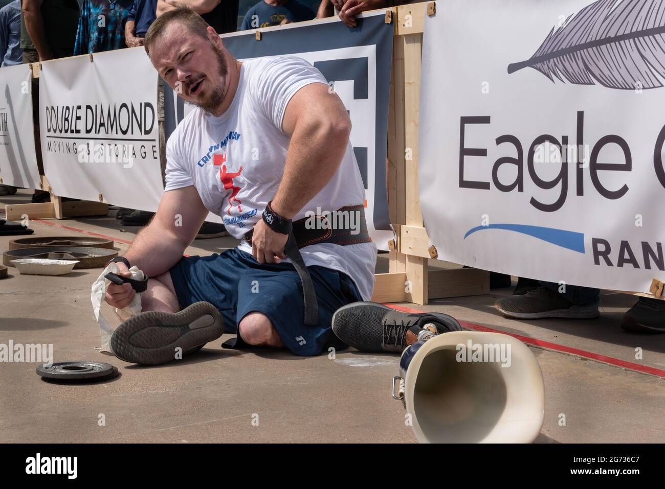 Weightlifter Joshua Smith looks at camera, sitting on sidelines of Crown Mountain Strongman Championship, his prosthetic leg on ground next to him. Stock Photo