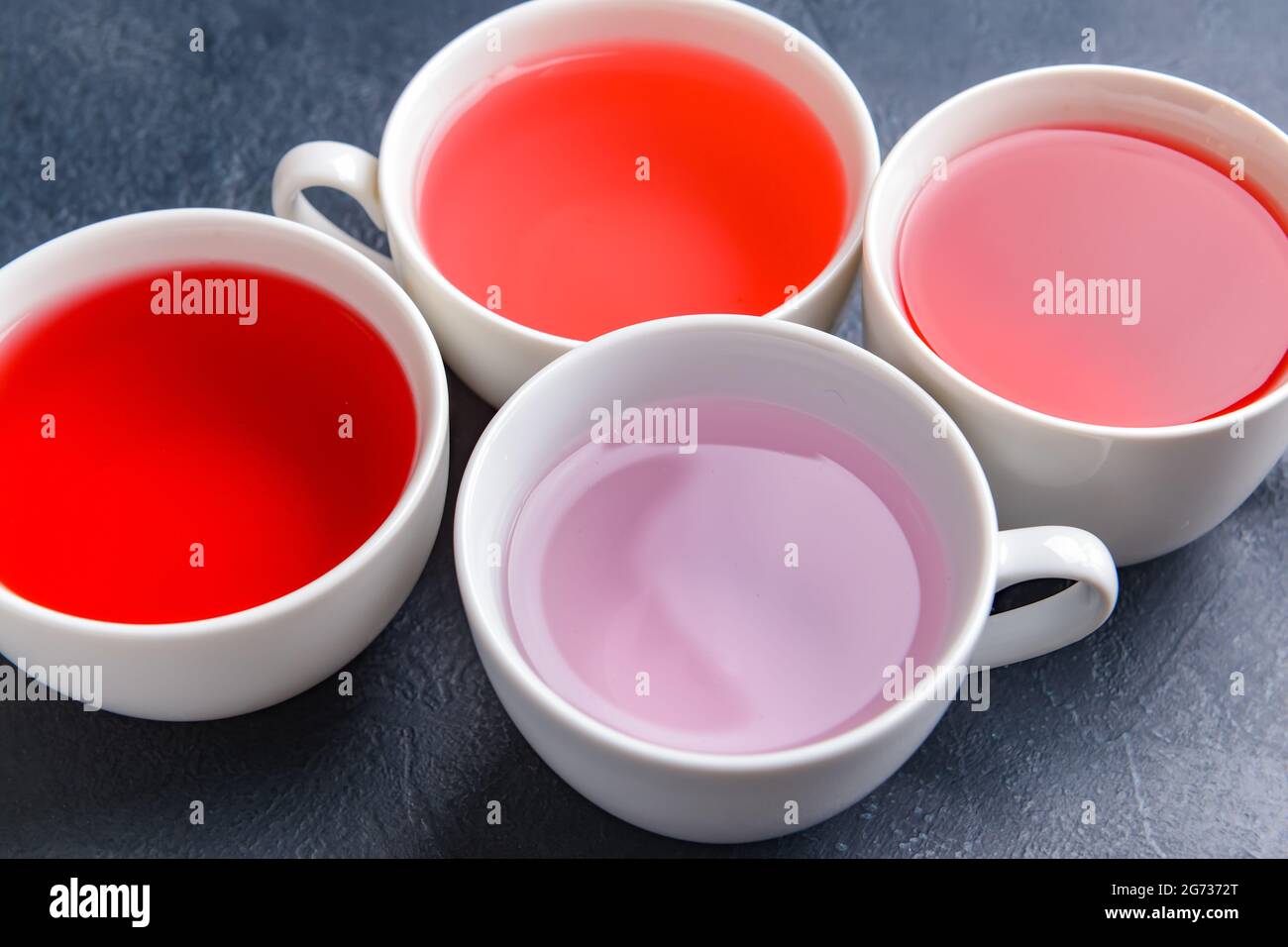 Cups with different types of hot tea on dark background, closeup Stock