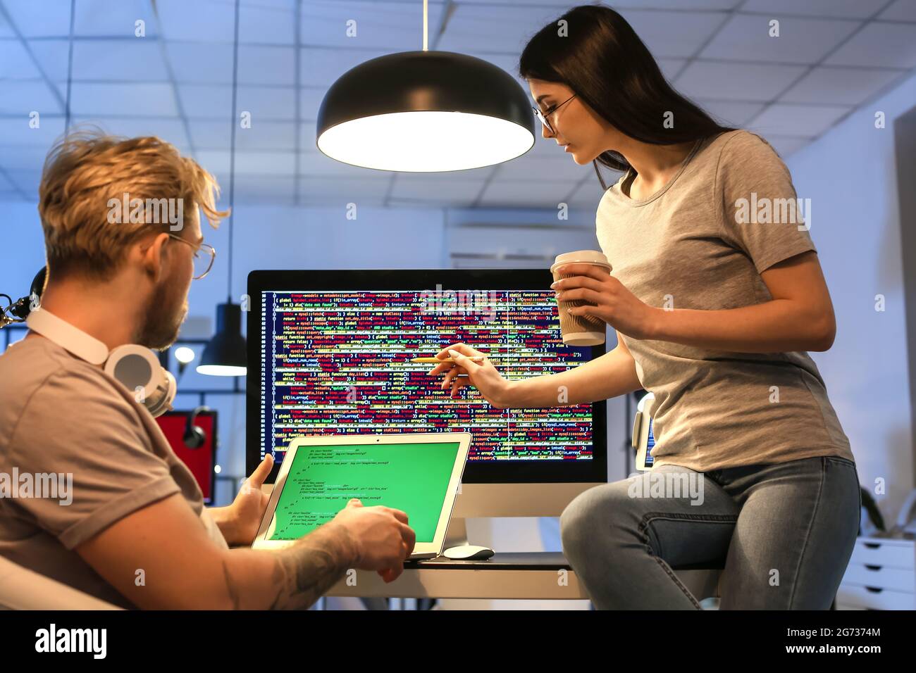 Young programmers working with laptop in office at night Stock Photo