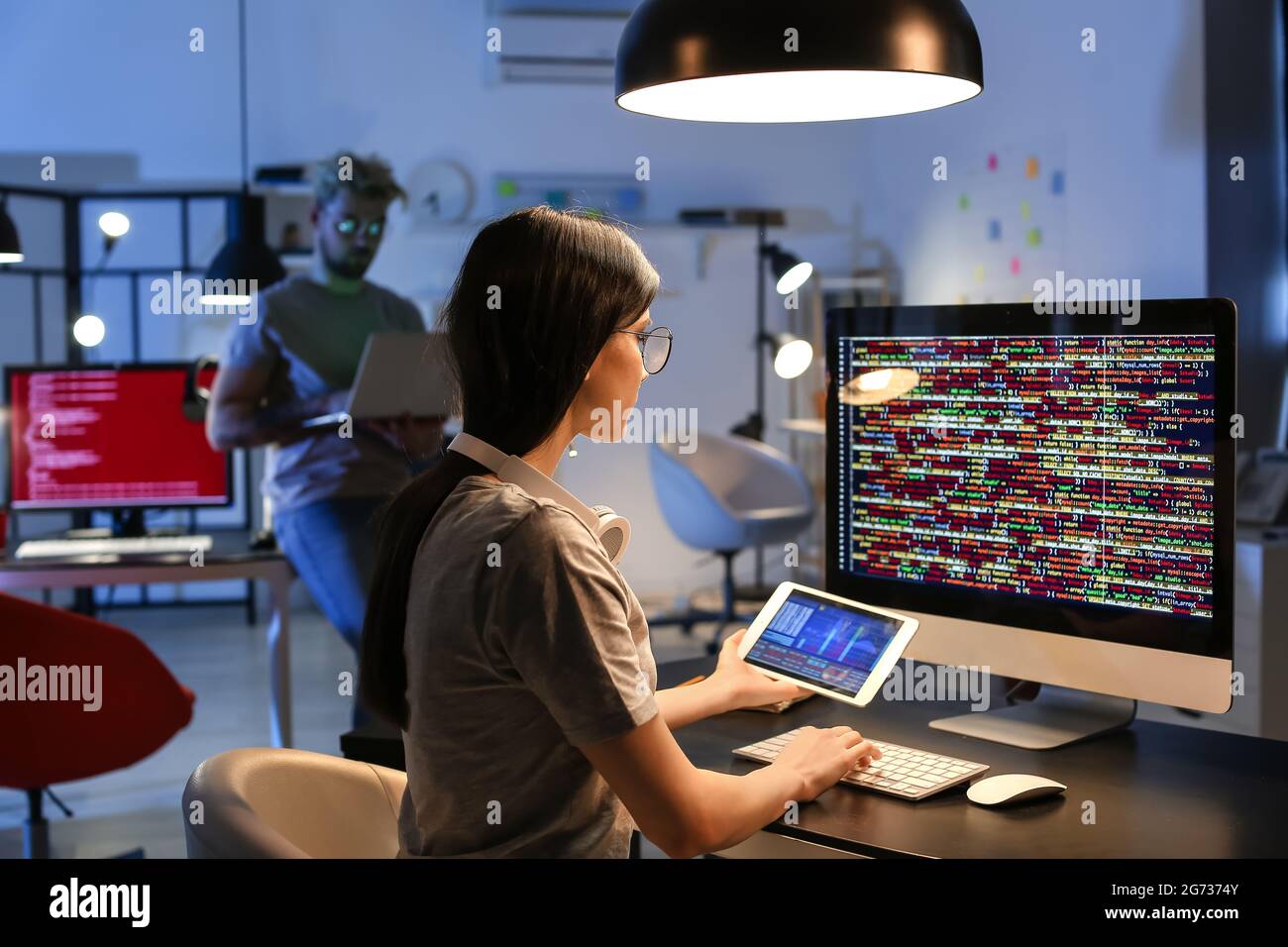 Female programmer working with computer in office at night Stock Photo