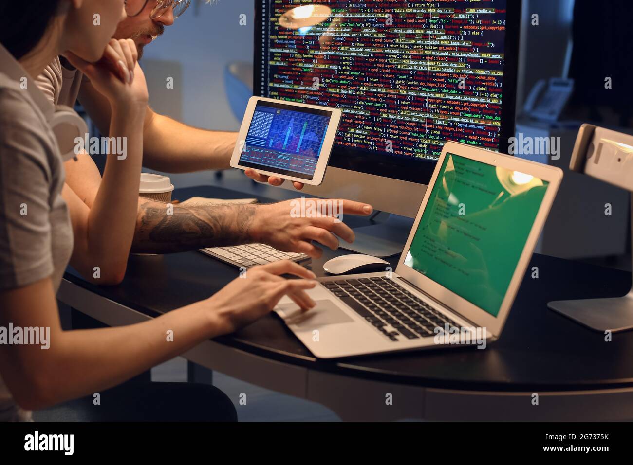 Young programmers working with laptop and tablet computer in office at night Stock Photo