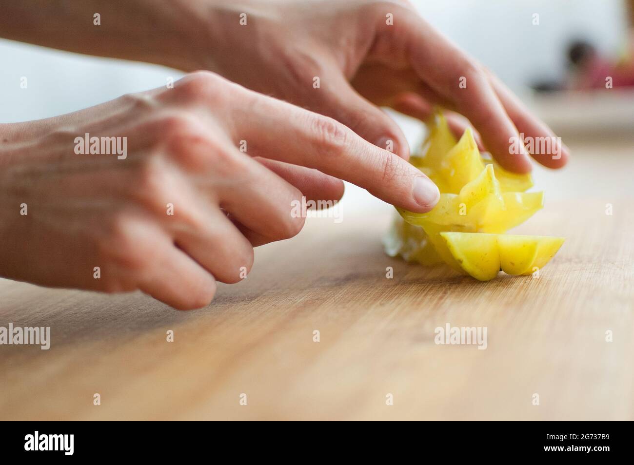 Female hands are holding slice of exotic ripe starfruit or averrhoa carambola. Healthy food, fresh organic star apple fruit Stock Photo