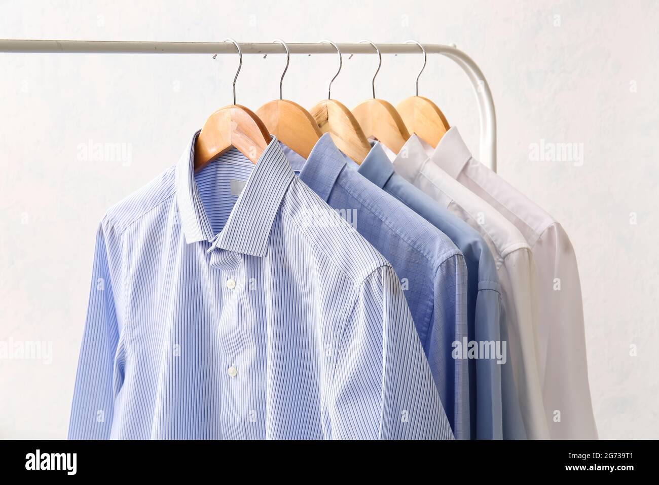 Rack with clothes after dry-cleaning on light background Stock Photo