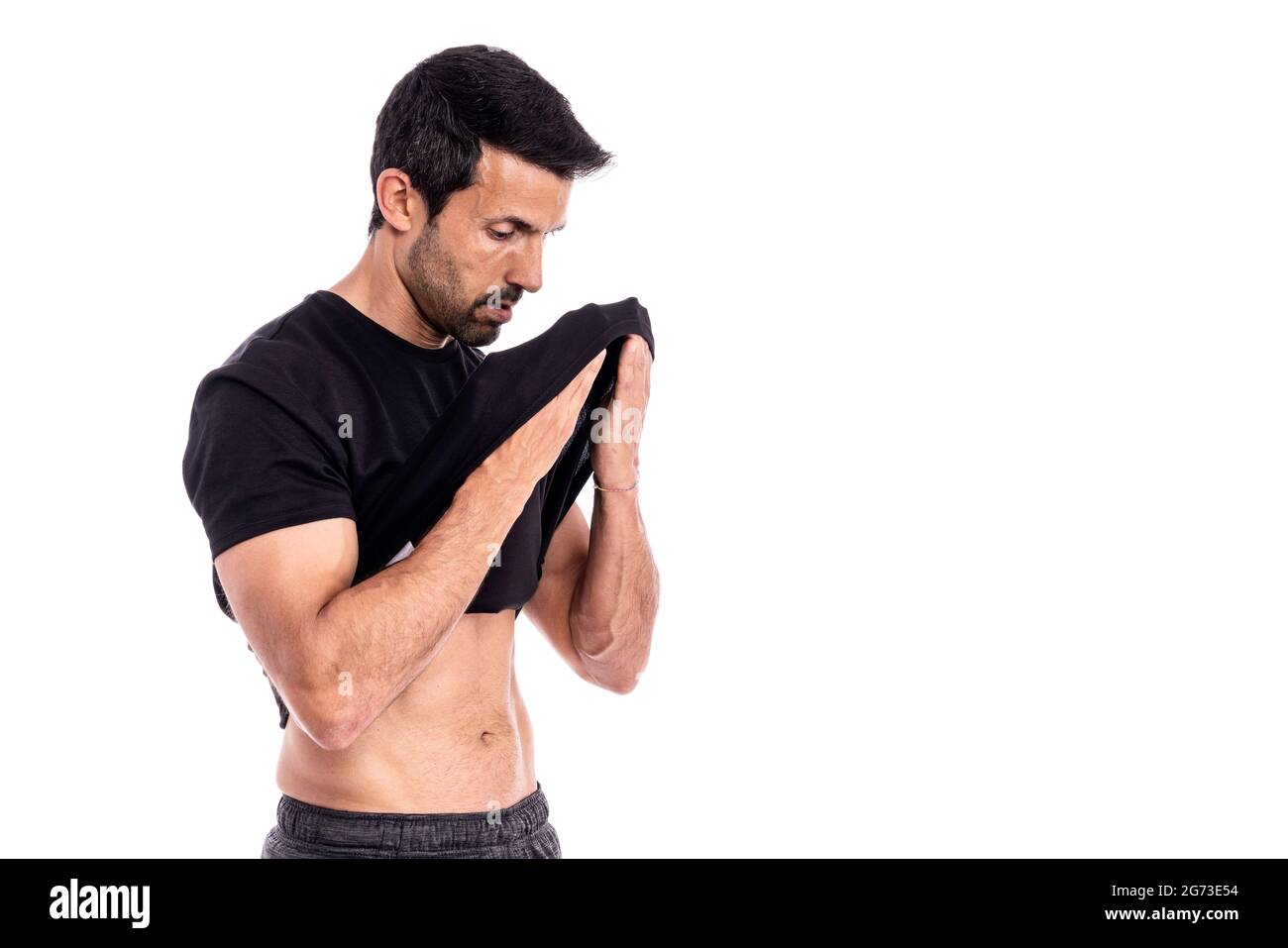 European man, caucasian, an athlete, wipes sweat from his forehead with a T-shirt. After a hard workout. Stress and fatigue. On a white background. Stock Photo