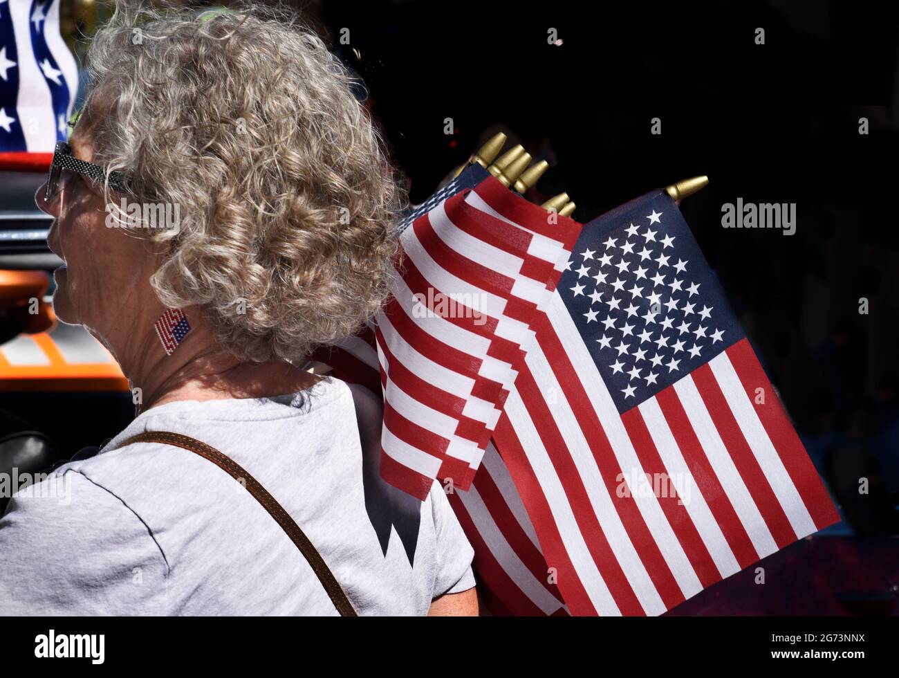 A woman distributes small American flags at a Fourth of July classic car show in Santa Fe, New Mexico. Stock Photo