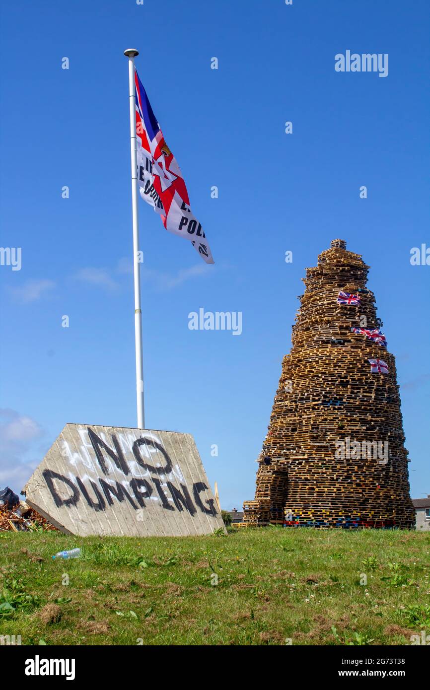 9 July 2021 A No Dumping sign placed beneath a Union Flag erected at the site of the Protestant Kilcooley Estate bonfire which is being built for burn Stock Photo