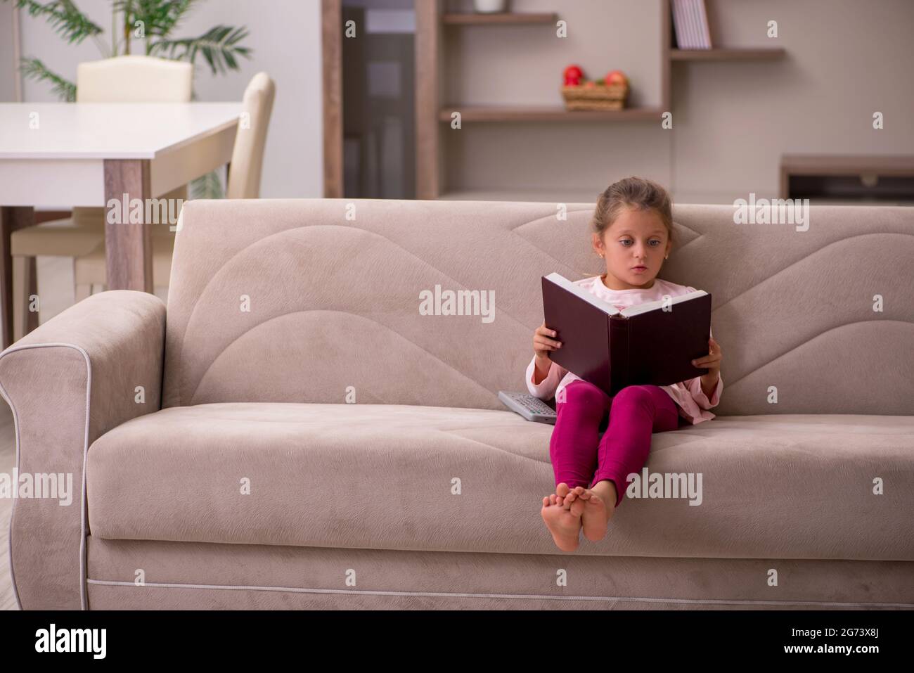 Little girl reading book at home Stock Photo - Alamy