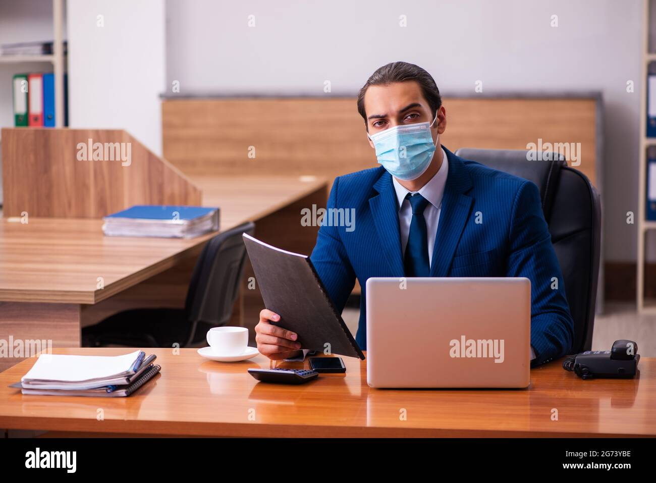 Young employee working in the office wearing mask Stock Photo - Alamy