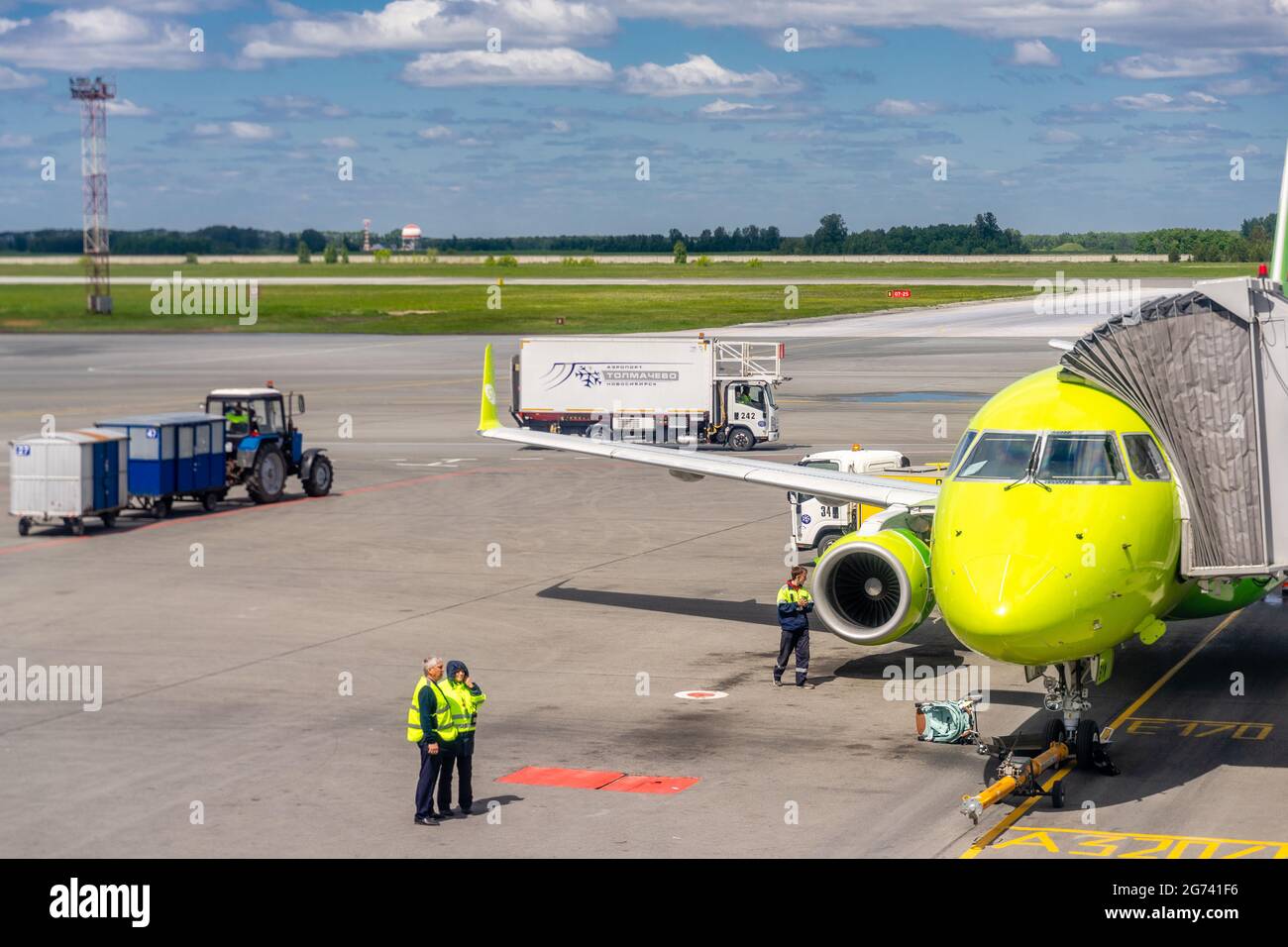 Front of S7 airlines airplane, airport personnel and moving vehicles on taxiway tarmac of Tolmachevo international airport, Novosibirsk, Russia Stock Photo