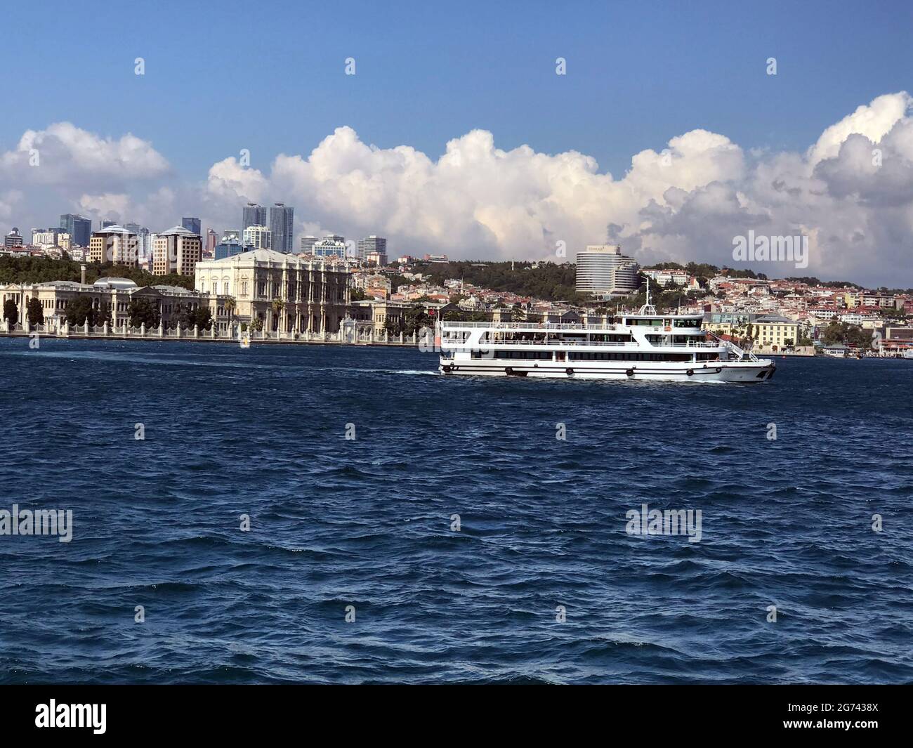 A ferry boat passes the Ciragan Palace on the Bosphorus Sea in  Istanbul, Turkey Stock Photo