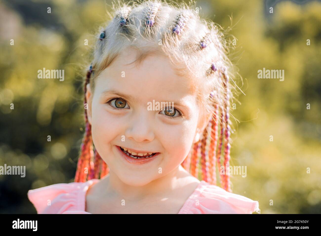 Girl smiling with hairstyle dreadlocks. Kid with fashionable hair