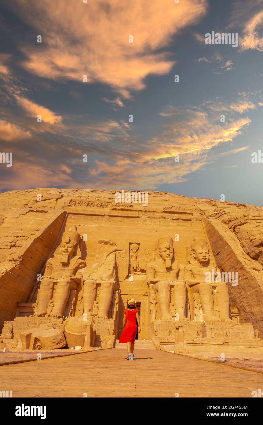 A vertical shot of European tourist in red dress walking towards the Abu  Simbel Temple in Egypt Stock Photo - Alamy