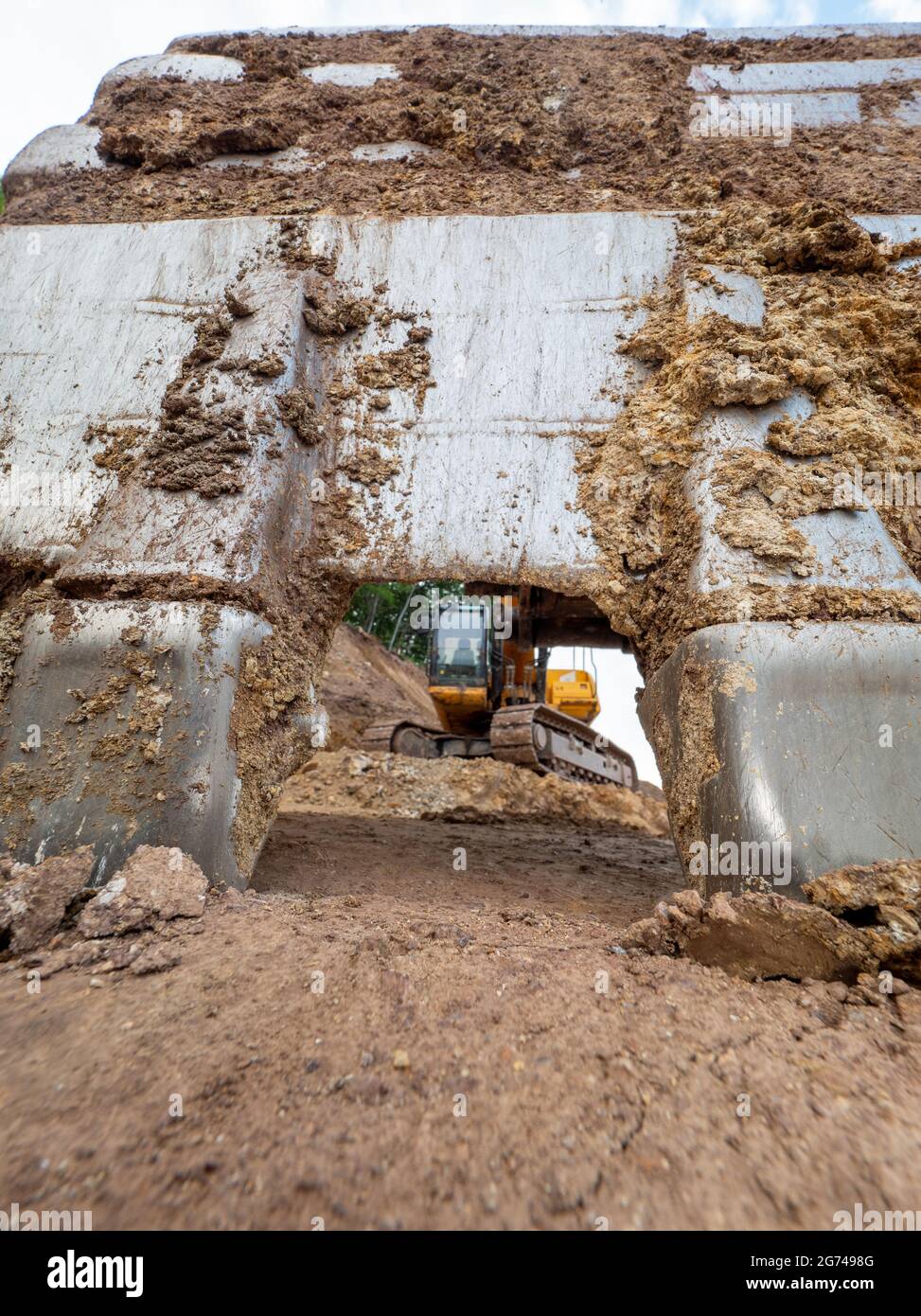 Cracked earth under excavator bucket bite the ground. Backhoe bucket. Green mind theme Stock Photo
