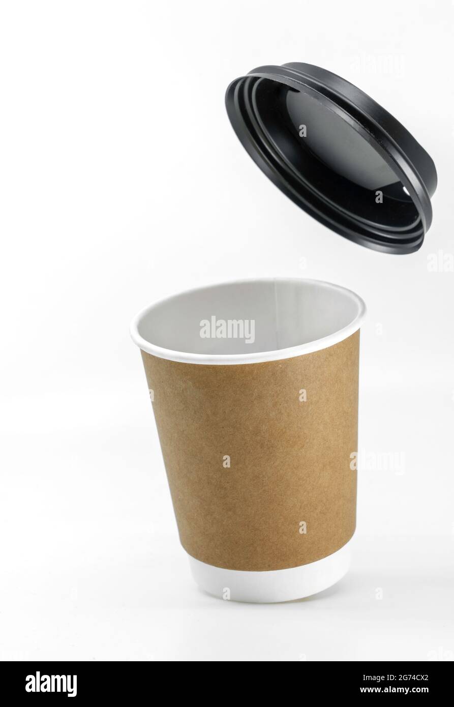 Close up slightly tilted coffee paper cup or take out coffee paper cup with lid flying on the top. Image on white background. Blank space for design a Stock Photo