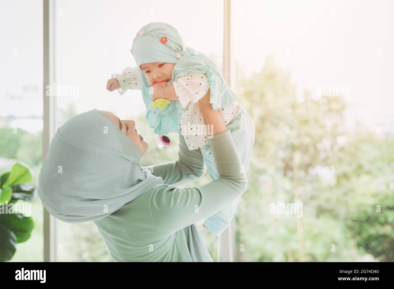 Muslim family or Islam mother with her healthy baby happiness playing together at lovely home. single mom. Stock Photo